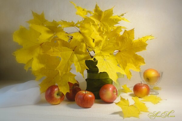 Nature morte avec des feuilles dans un vase et des pommes