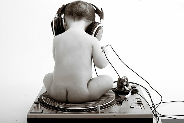 A child with headphones on a record, in gray shades