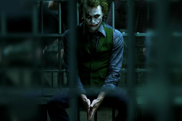 Joker seduto dietro le sbarre, con uno sguardo triste