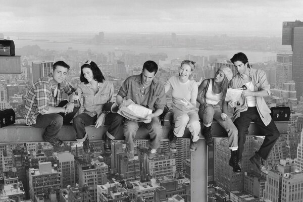 Friends are sitting on a pipe against the background of the city