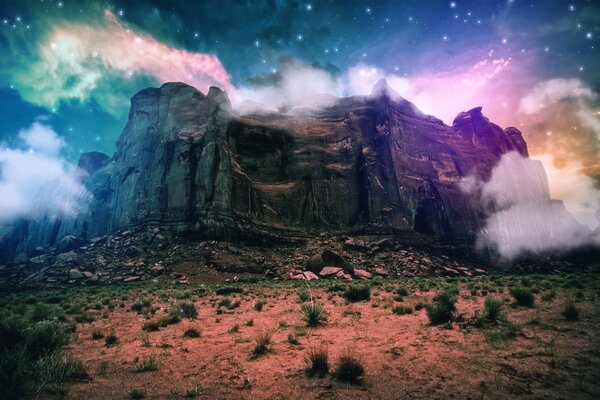 A rock in starry clouds and red sand