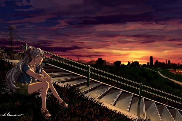 Chica sentada en la hierba en el fondo de la puesta de sol