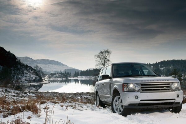 SUV en medio de la nieve y el lago