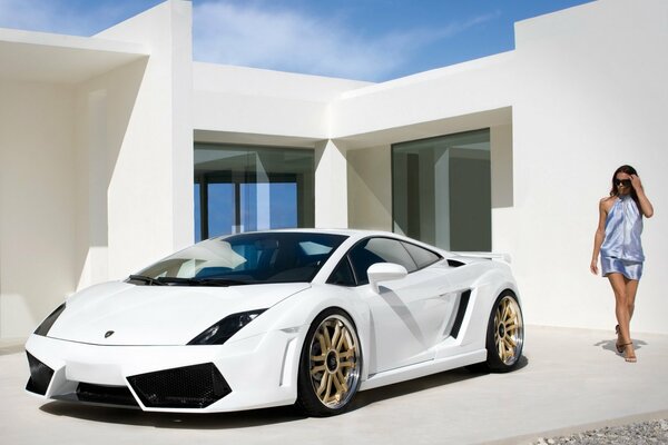 Hermosa chica de pie en la casa al lado de Lamborghini