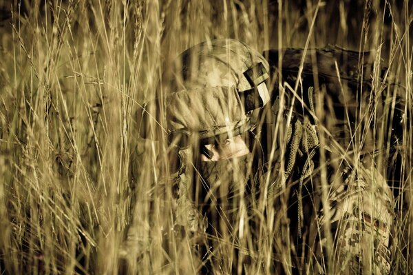 A soldier with a machine gun lying in ambush in the grass