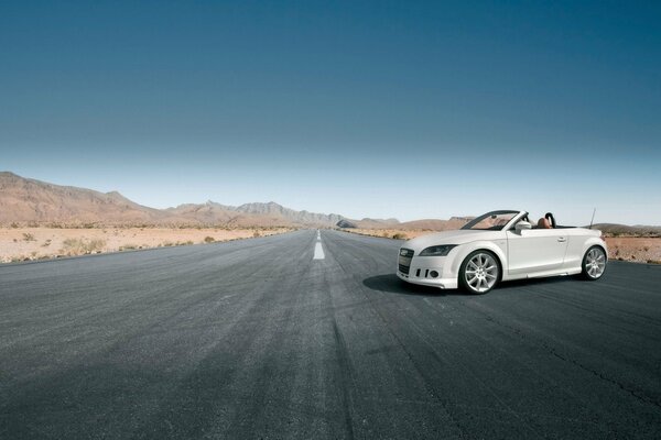 A white Audi convertible is parked on an empty road