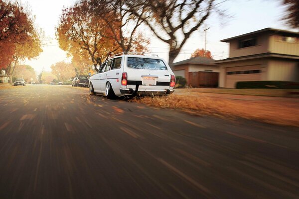 A white car drives through the autumn city