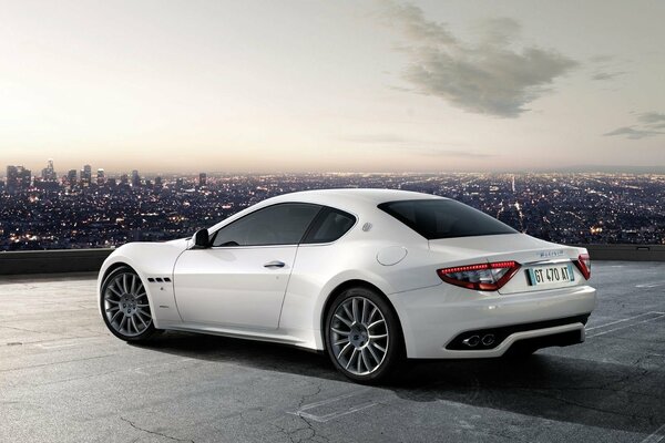 Sur le fond de la ville du soir se trouve une Maserati blanche