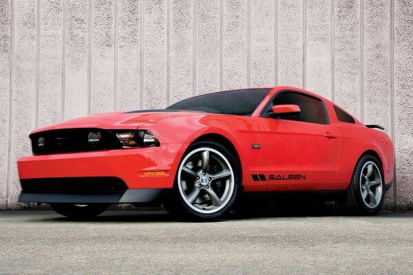 Mustang rojo en el fondo de la pared con vidrios polarizados