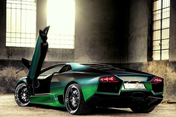 Dark green lamborghini in a building with large windows