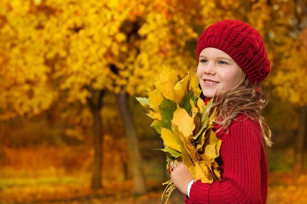 Niña con un ramo de hojas de otoño