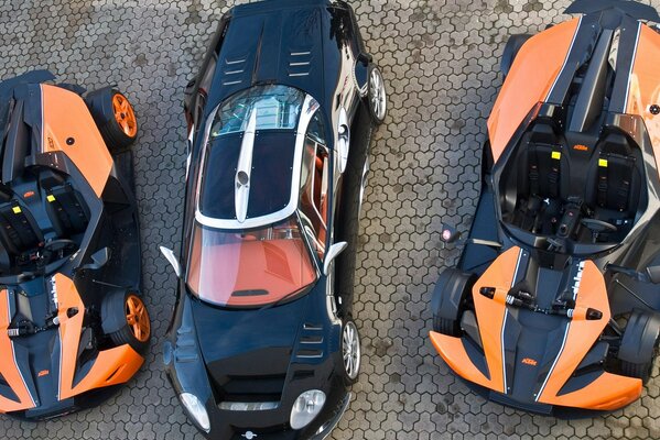 Three black and orange cars are parked in the parking lot