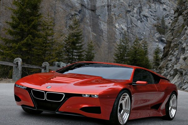 Coche BMW color rojo contra las rocas