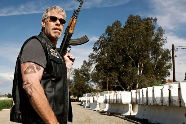 Schauspieler zum Leder-Eigelb mit Maschinengewehr Ron perlman