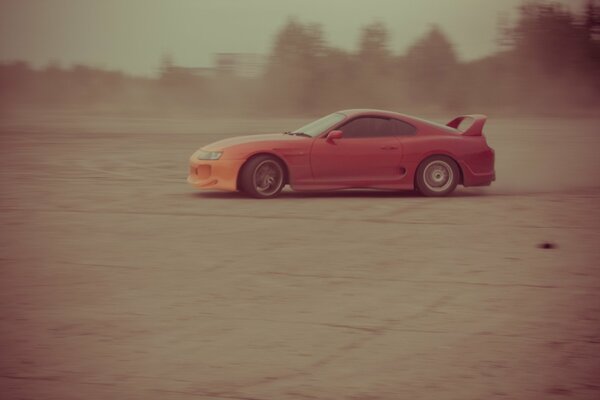 Red car. Drifting , blowing dust