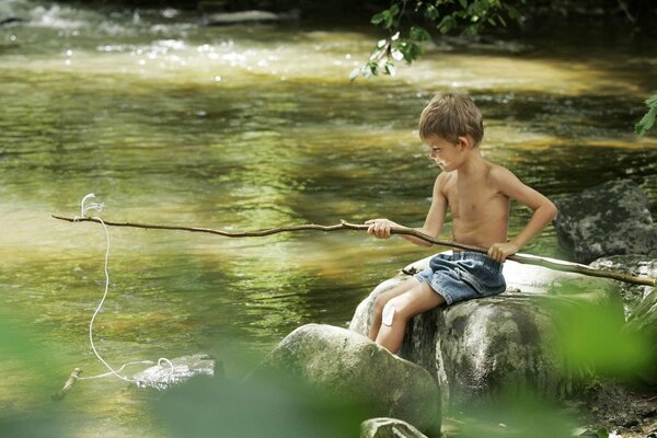 Niño pescando en el río con una caña de pescar
