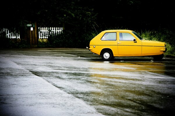 The yellow car is standing on wet asphalt