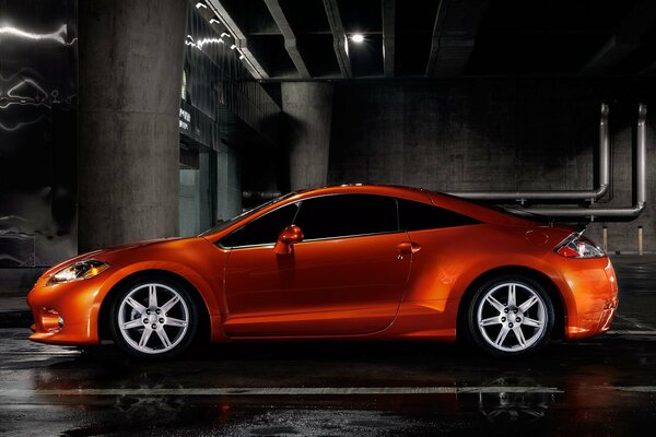 Mitsubishi orange dans le parking souterrain avec mur en métal