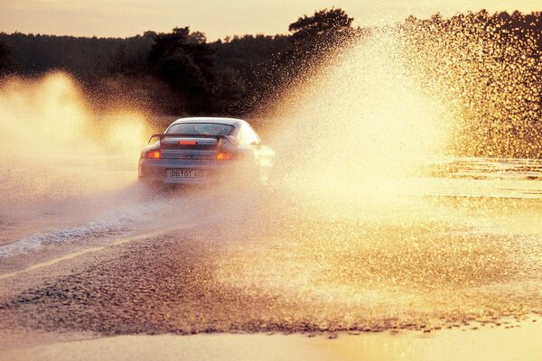 The car rides on the water and splashes fly