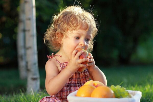 Dziewczyna zjada jabłko z kosza z owocami
