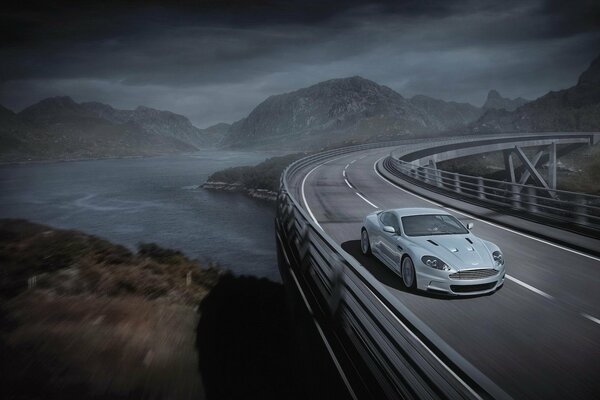 Grey Aston Martin drives across the bridge