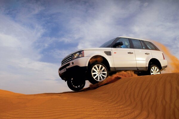 Jeep blanco salta sobre el terciopelo de la arena