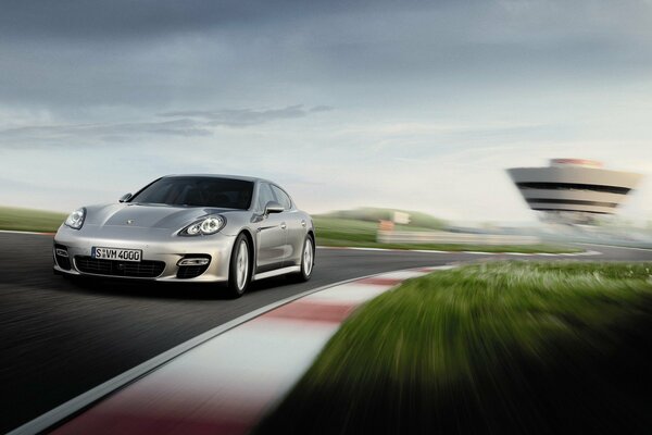 Srebrne Porsche ponamera na drodze z dużą prędkością