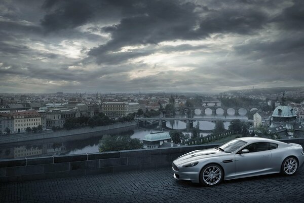 Aston Martin on the background of a city with clouds