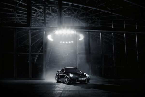 Porsche nera in garage con luce direzionale su auto