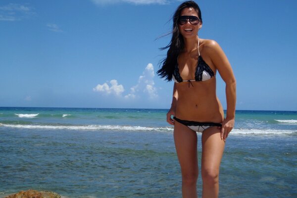 Jeune fille debout sur le bord de la mer et souriant