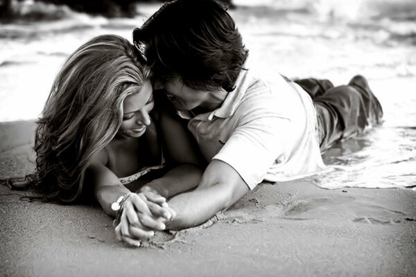 Le gars et la fille se trouvent sur le sable. Image en noir et blanc