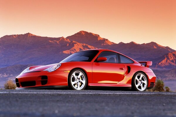 Porsche rojo en el fondo de las montañas del atardecer