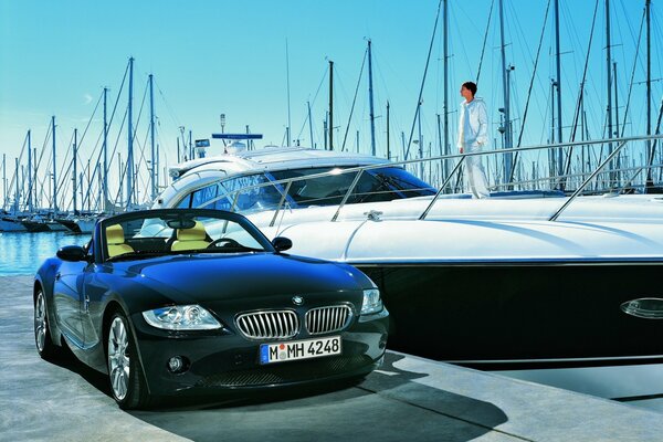 BMW obok eleganckiego jachtu z osobą na pokładzie