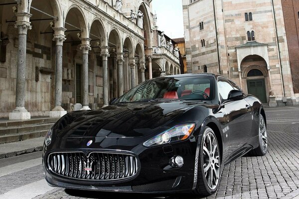 A black maserati stands on the road in the city