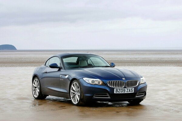 A blue BMW car is parked on the ocean