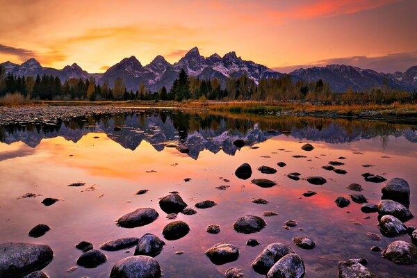 Sunset on the shore of a lake with rocks