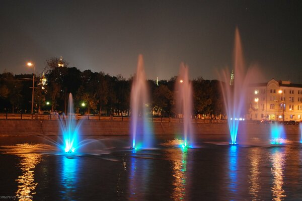 LED fountains on the river among the evening city