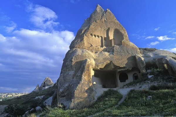 A house carved into a pointed rock among green grass