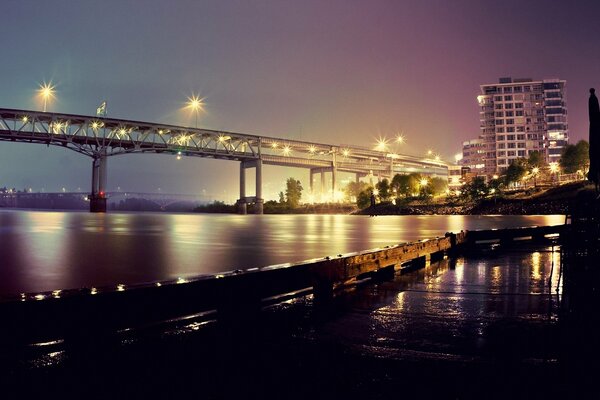 Vista nocturna del puente con las luces encendidas en el río