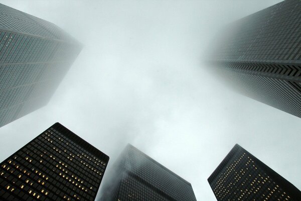 Wolkenkratzer, die im Nebel ertrinken. Ansicht von unten