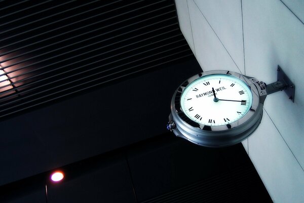 Blue clock face on white parquet against a black wall with reddish reflections