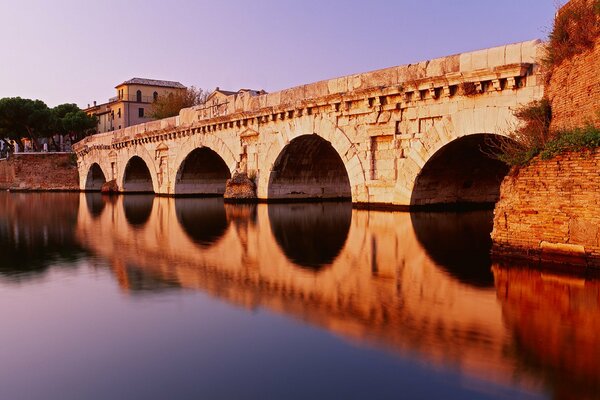 A bridge reflecting in the calm surface of the water, creating the illusion of round holes