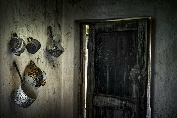 An old door in a room with dirty dishes on the wall