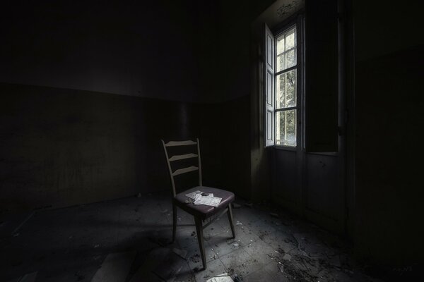 A gloomy room with a window and an armchair