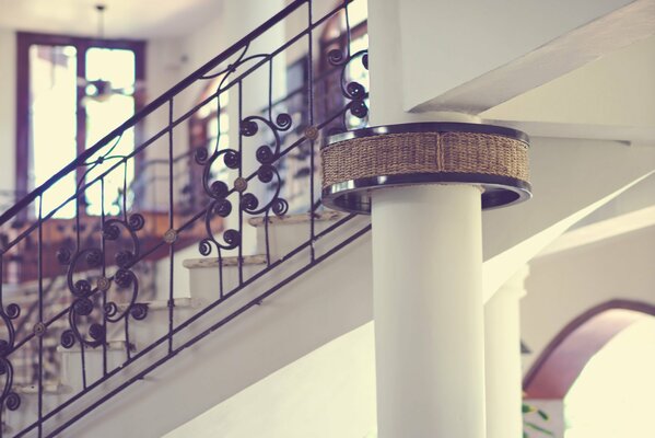 Escalera de metal calado y columna blanca en la casa