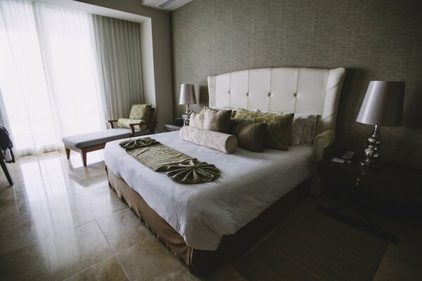 A bedroom with a large bed and a lot of pillows on the bed