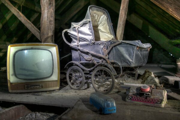 Vieux téléviseur et poussette dans le grenier