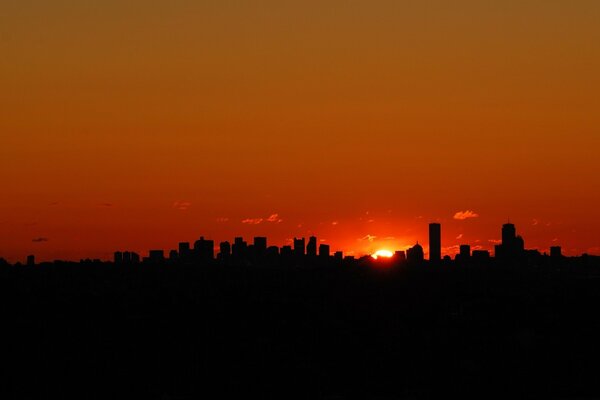 The silhouette of a big city against the background of a red sunset