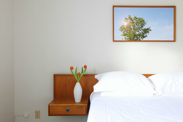 A vase of flowers on the bedside table near the bed