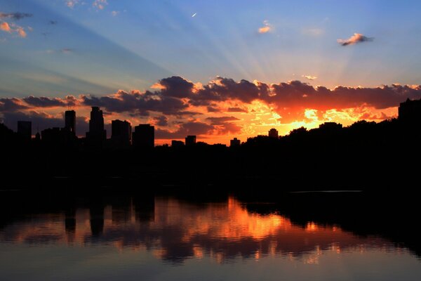 La hermosa puesta de sol sobre la ciudad se refleja en el agua